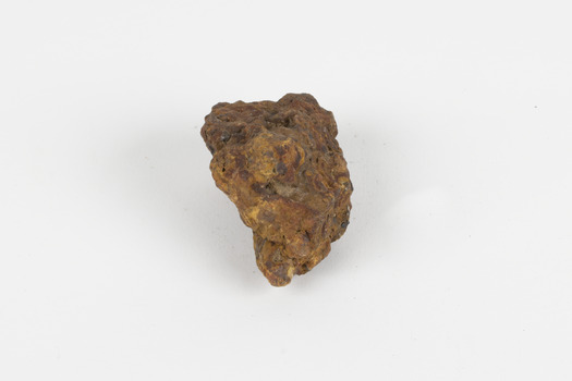 a palm-sized solid mineral specimen in shades of brown, orange and grey