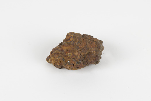 a palm-sized solid mineral specimen in shades of brown, orange and grey