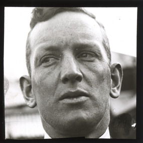 A monochrome photograph within a square frame featuring a close-up image of a man's face.