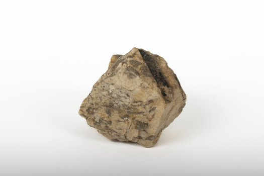 A small textured caramel-coloured granite rock with brown marbling. On the upper right side is an oblong indentation revealing shiny deep brown to black layer.