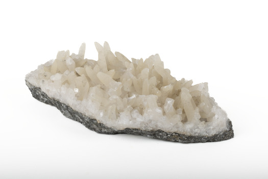 Mineral with a stone coloured base with white crystal like structures erupting from the base in erratic upwards directions.