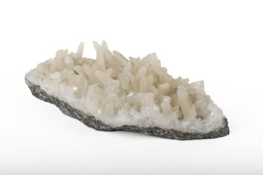 Mineral with a stone coloured base with white crystal like structures erupting from the base in erratic upwards directions.