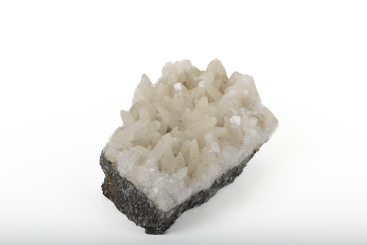 Mineral with a stone coloured base with white crystal like structures erupting from the base in erratic upwards directions.