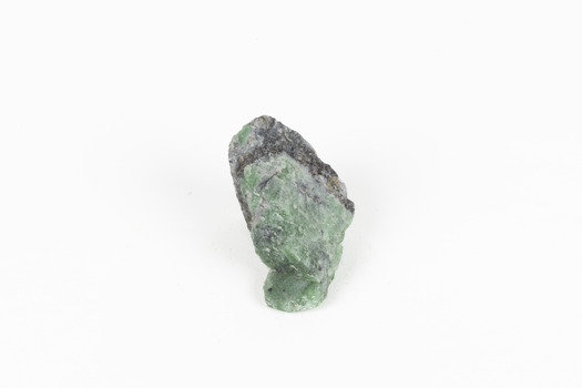 A small solid mineral specimen that is primarily pale green and blue-grey with speckles of beige and white.