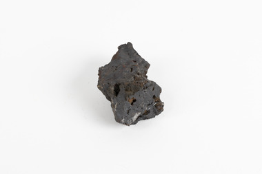 A small solid mineral specimen that is blue-grey in colour with rust brown specks throughout.