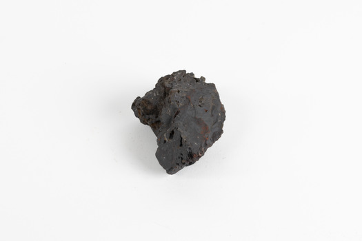 A small solid mineral specimen that is blue-grey in colour with rust brown specks throughout.
