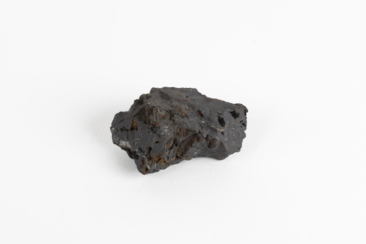 A small solid mineral specimen that is blue-grey in colour with rust brown specks throughout.