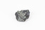 Palm-sized mineral of primarily grey colour, small red gemstones visible, green patches.