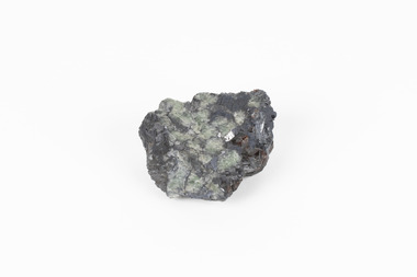 Palm-sized mineral of primarily grey colour, small red gemstones visible, green patches.