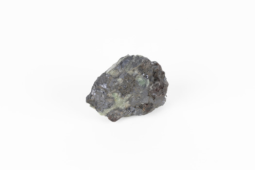 Palm-sized mineral of primarily grey colour, small red gemstones visible, green patches.