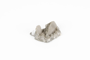A small sized solid mineral specimen in shades cream and grey