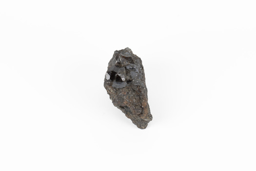 Coin-sized solid mineral in shades of black and red with black shiny points.