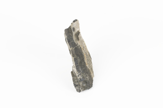 Coin-sized solid mineral with tiny crystals and shades of black and beige situated on side position.