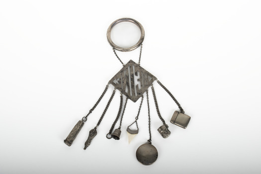 A decorative silver belt hook with small household object attached by chains to a suspended name plate