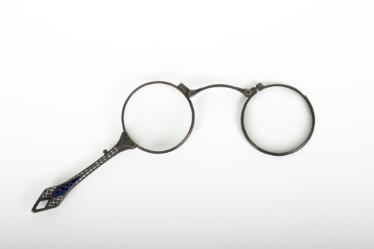 A pair of spectacles with a decorative handle attached.