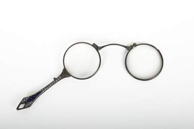 A pair of spectacles with a decorative handle attached.