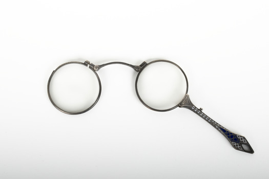 A pair of spectacles with a decorative handle attached.