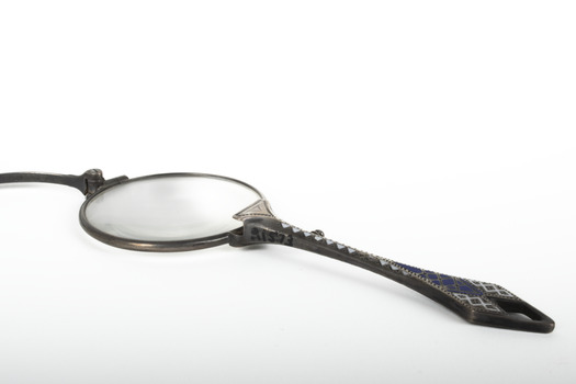 A pair of spectacles with a decorative handle attached.