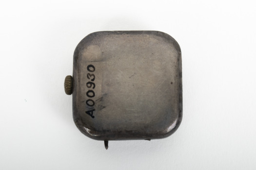 Small silver square with gold turner mechanism on left side of item. 