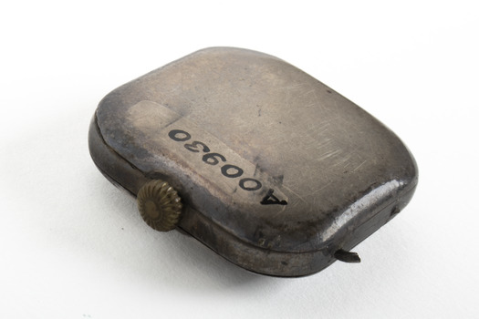 Small silver square with gold turner mechanism on left side of item. 