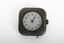 Small silver square clock with gold turner mechanism on right side of item. Clock is stuck on five past one.