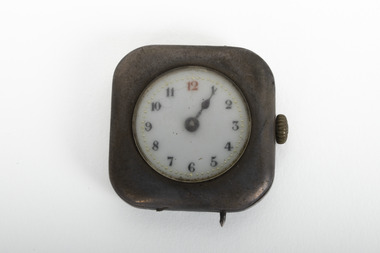 Small silver square clock with gold turner mechanism on right side of item. Clock is stuck on five past one.
