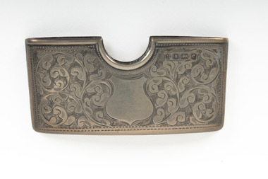 The front of a rectangular silver card case that is etched with an ornate design.