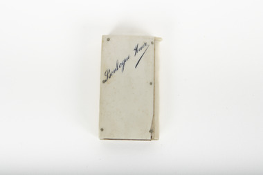 A small white rectangular box with cursive writing on top.