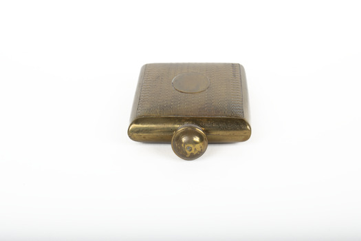 A small lidded square brass bottle embossed with a geometric pattern.