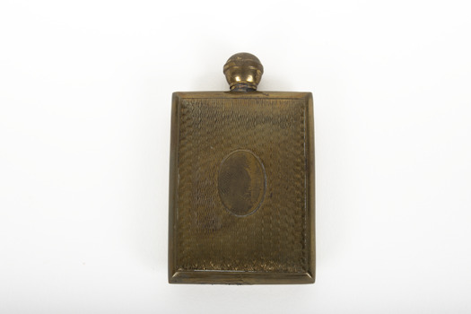 A small lidded square brass bottle embossed with a geometric pattern.