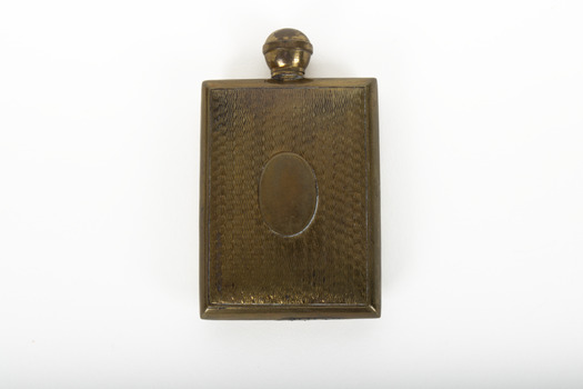 A small lidded square brass bottle embossed with a geometric pattern.