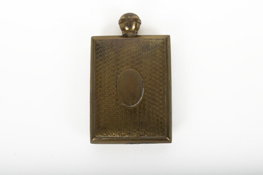 A small lidded square brass bottle embossed with a geometric pattern.