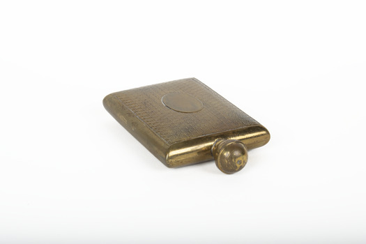 A small lidded square brass bottle embossed with a geometric pattern.