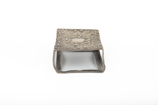 A silver rectangular match case with an embossed top.