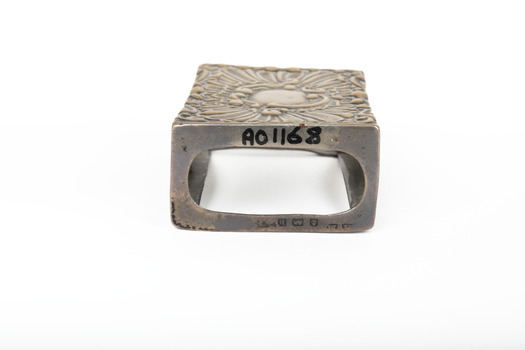 A silver rectangular match case with an embossed top.