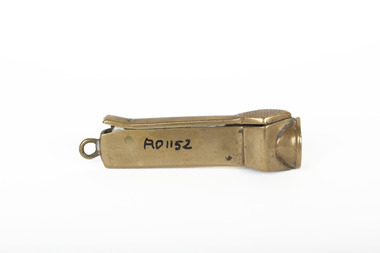 Small bronze metallic cigar cutter with an accession number written in the middle, positioned on its back. 