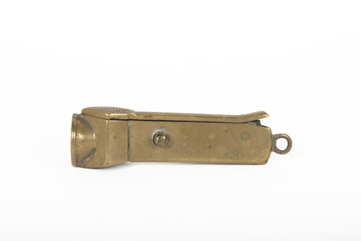 Small bronze metallic cigar cutter with an accession number written in the middle, positioned on its back.