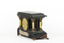 An angled reverse view of a Seth Thomas black mantle clock with green marbling detail. The Seth Thomas Clock Company logo is laid in a gold-toned back door. On either side of the clock are white pillars with bronze-coloured base and top. The clock also features ornate gold claw feet and fine gold painted detailing. A torn maker's label is affixed to the back setting out the name 'Adamantine' and directions to use the clock.  