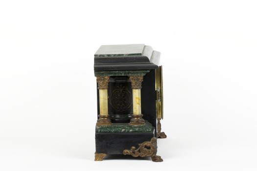 Side view of a Seth Thomas black mantle clock with green marbling detail. The clock also features ornate gold claw feet and fine gold painted detailing. From this angle, the front and rear white pillars are visible.