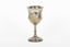 A silver trophy with an engraved flower design going around the cup. A seperate flower deign ring encircles the rim of the cup.