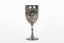 Silver cup in the shape of a wine glass, as the cup tapers to a pedestal. The cup is engraved with branches and leaves, the base engraved with lines, dots and a half-moo pattern. 