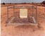 Desert grave stone of Dost Mahomet surrounded by singular pipe fence.