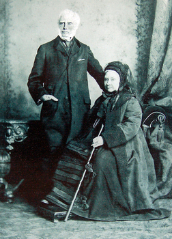 Bearded man standing beside a seated woman dressed in nineteenth century European clothing