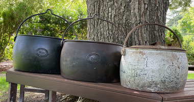 Set of 3 cast iron cooking pots, L-R 9 gallons, 7 gallons and 5 gallons