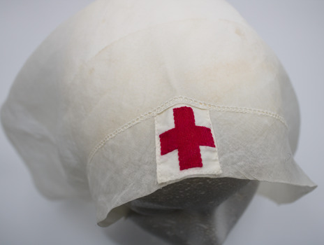 Close-up of centre front of white head scarf with white cloth patch with red cross stitched into it. Shows one inch hem stitch detail.