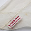 Detail of manufacturer's label stitched into hem of white headscarf. White label with red cotton stitching