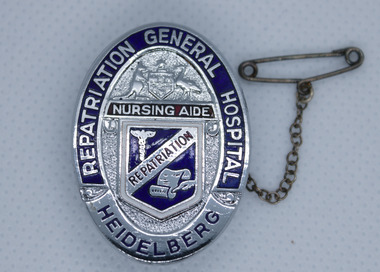 Oval shape silver badge with chain and safety pin