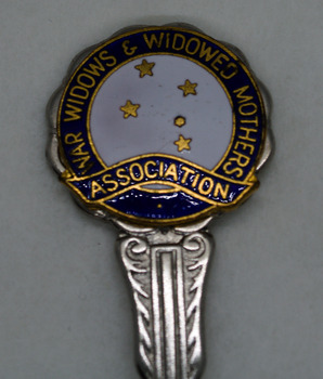 Detail of circular head of silver spoon, white enamel centre with gold Southern Cross stars and blue edge with gold writing