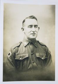 Sepia toned photograph of soldier in uniform with Rising Sun Badges on collar. Australia Badge on epaulettes. Colour Patch on right arm.