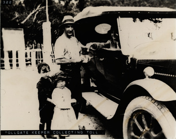Tollkeeper collecting toll from car driver with two children beside him